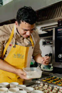 Ein Koch steht in der Küche und richtet Essen an.