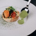 Eine Forelle serviert auf einem Teller mit grüner Sauce.