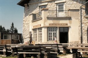 Ein Gasthof in den Bergen mit Sitzmöglichkeit draußen.