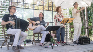 Eine Performance einer Band, die in einem Glashaus im Wald spielt.
