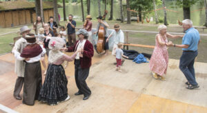 Leute tanzen auf einem Holzparkett während im Hintergrund eine Band spielt.