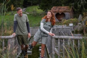 Zwei Wanderer gehen über einen Erlebnis Pfad und lachen.