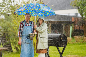 Zwei Personen beim Grillen im Regen mit Regenschirm © Giuseppe Lombardo iStock Getty Images Plus