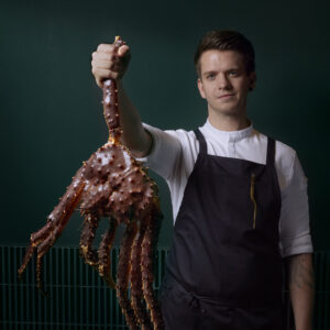 Zwei-Hauben-Koch Bernhard Zimmerl hält eine Krabbe in die Kamera.