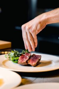 Feinarbeit am Teller: Küchenchef Ogun Yildirim arbeitet gemeinsam mit einer Kollegin an der Anrichte von Beilagen und Fleisch.